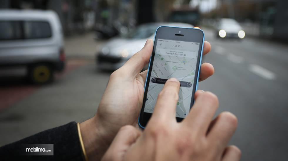 konsumen Uber sedang memegang aplikasi Uber