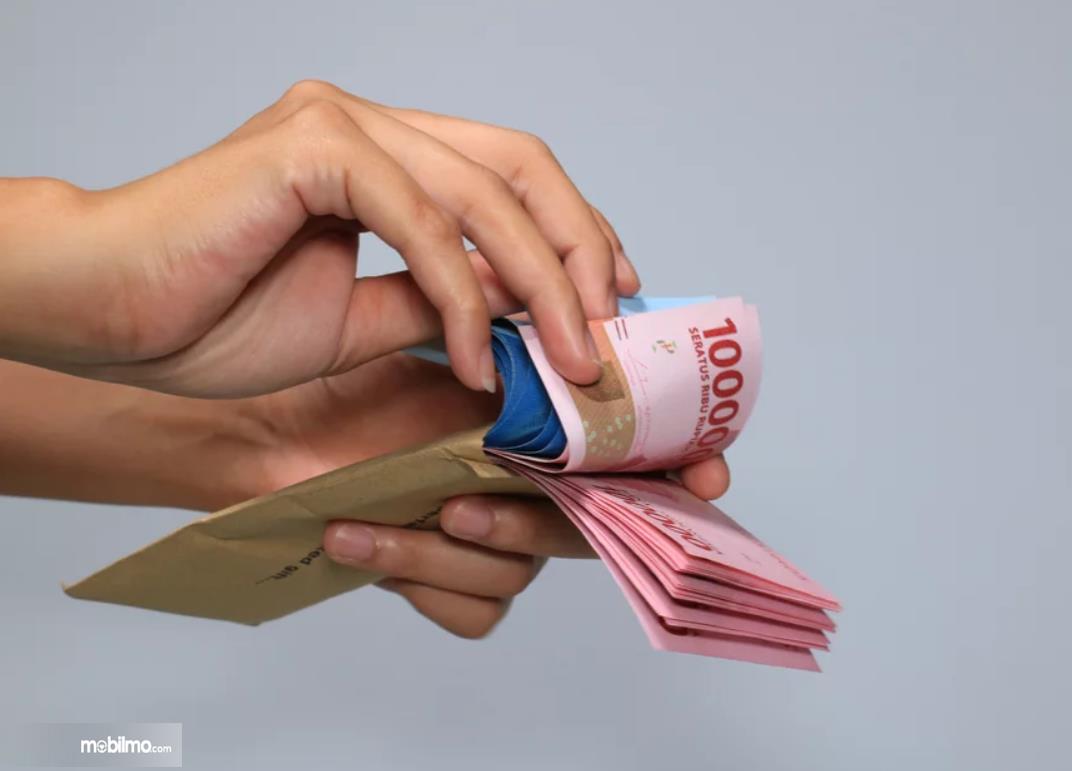Foto menunjukkan uang tunai dikeluarkan dari amplop