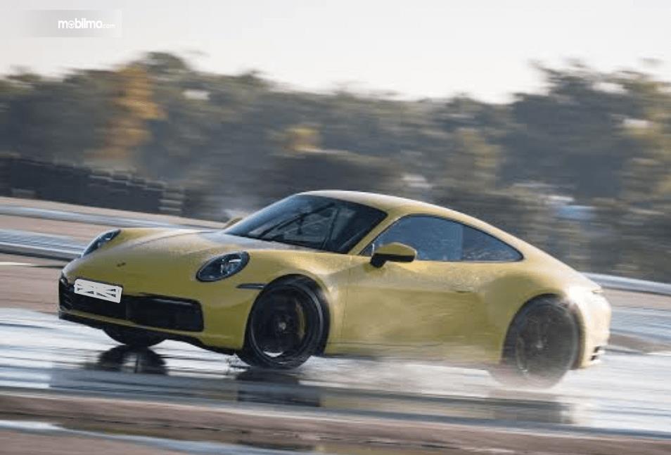 Gambar ini menunjukkan mobil Porsche 911 terbaru warna kuning melintasi air