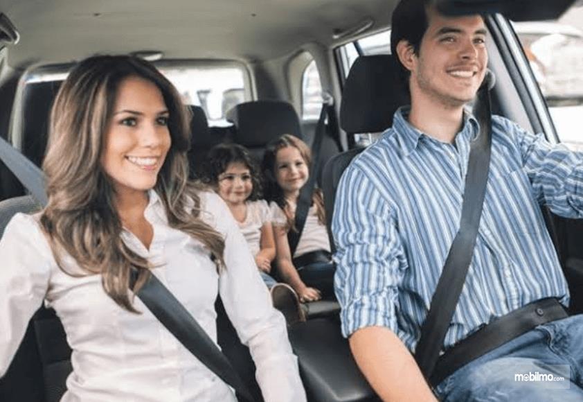 Gambar ini menunjukkan 2 orang dewasa dan 2 orang anak di dalam mobil