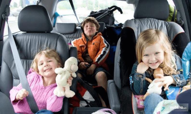 gambar ini menunjukkan 3 orang anak sedang di dalam mobil