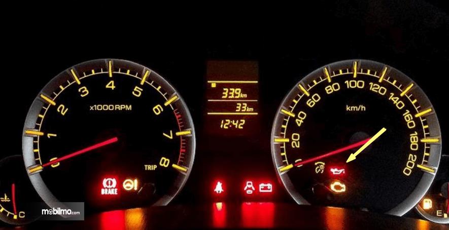 Gambar ini menunjukkan layar speedometer mobil dengan beberapa lampu indikator