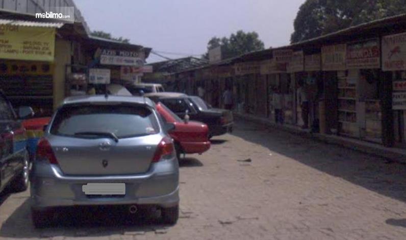 gambar ini menunjukkan beberapa mobil dan toko di dekatnya