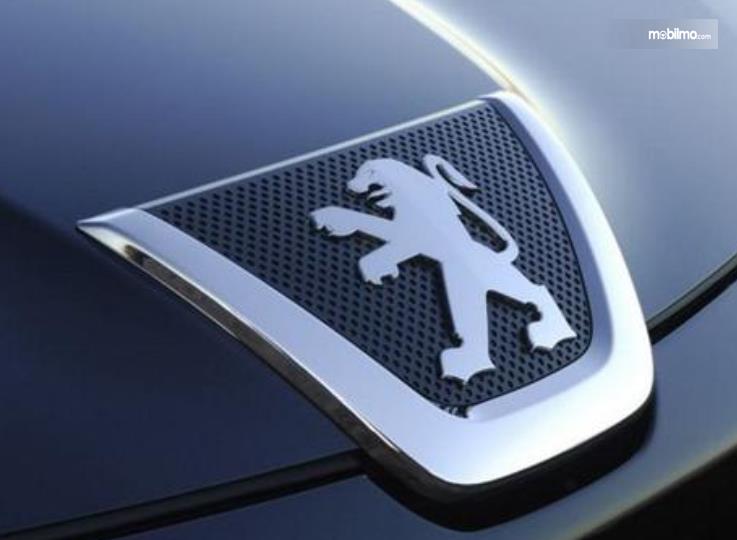 Gambar ini menunjukkan logo Peugeot pada mobil warna chrome