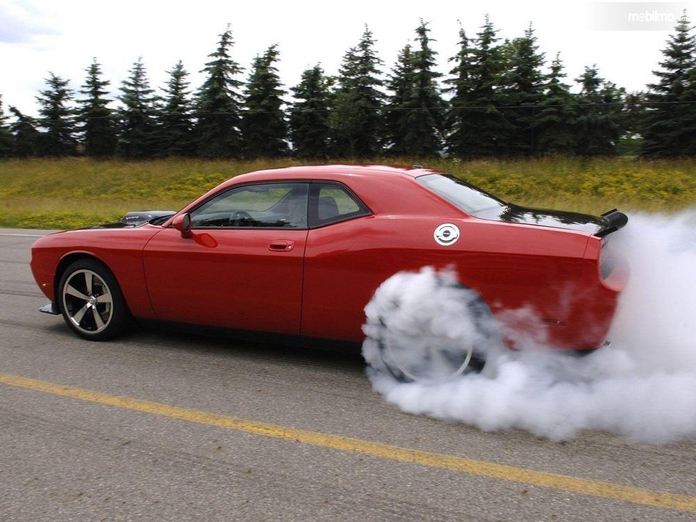 Foto menunjukkan mobil mengeluarkan asap saat di jalanan