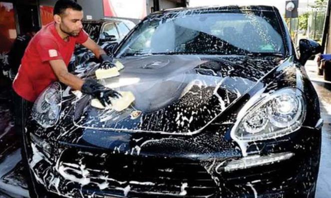 Gambar ini menunjukkan seorang pria sedang mencuci mobil
