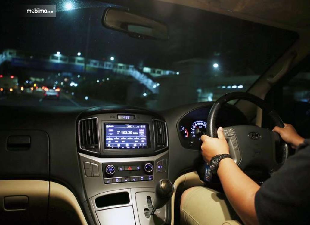 Gamnbar ini menunjukkan jalanan malam hari dilihat dari dalam mobil