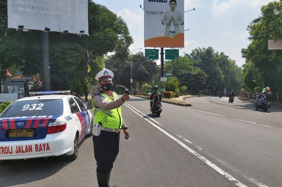 Gambar ini menunjukkan seorang petugas sedang mengatur lalu lintas
